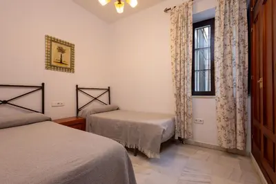 a bedroom with two beds and a window at Casa Palacio Luna in El Puerto de Santa María