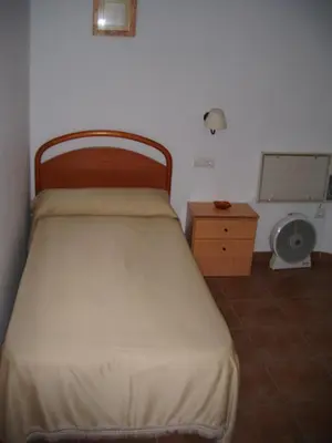 a small bedroom with a bed and a nightstand and a bed sidx sidx sidx at Pensión San Andrés I in Jerez de la Frontera