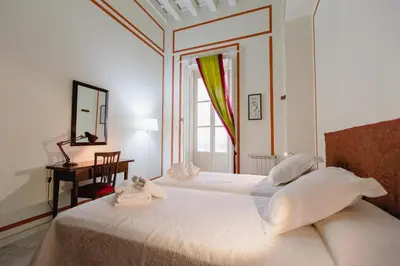 a bedroom with a bed and a desk and a window at Apartamentos La Botanica, Cadiz in Cádiz