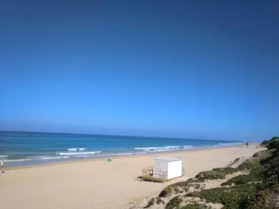 a beach with a bench and the ocean at Chalet en Roche in Conil de la Frontera