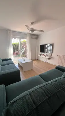 a living room with two green couches and a tv at Adosado Dulce Barrosa in Chiclana de la Frontera