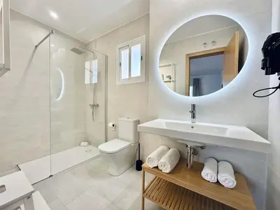 a white bathroom with a sink and a mirror at Apartamentos Turísticos Santo Rostro in Chipiona