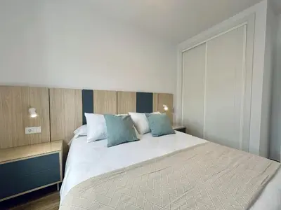 a bedroom with a large bed with blue pillows at Apartamentos Turísticos Santo Rostro in Chipiona