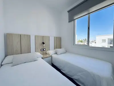 two beds in a room with a window at Apartamentos Turísticos Santo Rostro in Chipiona