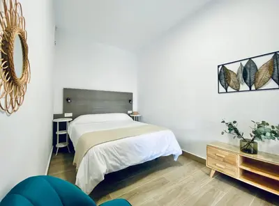 a bedroom with a large bed and a table at Apartamentos Turísticos Santo Rostro in Chipiona