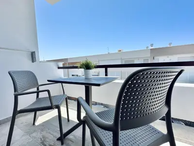 a table and chairs on a balcony with a table at Apartamentos Turísticos Santo Rostro in Chipiona
