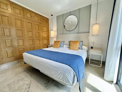 a bedroom with a large bed and a mirror at Hotel Apartamentos Marina Luz in Chipiona