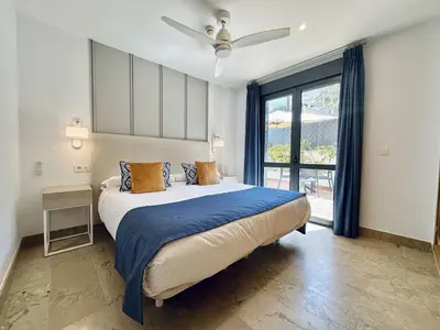 a bedroom with a large bed with a ceiling fan at Hotel Apartamentos Marina Luz in Chipiona