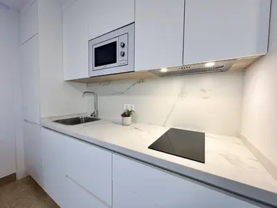 a white kitchen with a sink and a microwave at Hotel Apartamentos Marina Luz in Chipiona
