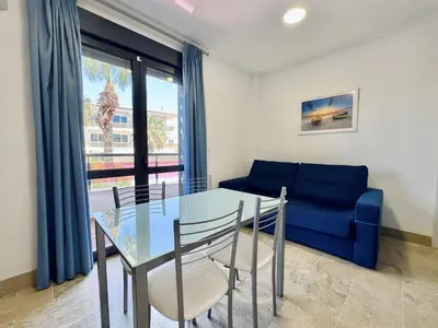 a dining room with a glass table and a blue couch at Hotel Apartamentos Marina Luz in Chipiona