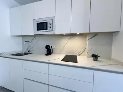 a white kitchen with a sink and a microwave at Hotel Apartamentos Marina Luz in Chipiona