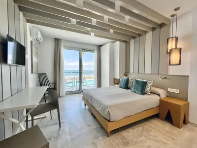 a bedroom with a bed and a table and a desk at Hotel Apartamentos Marina Luz in Chipiona