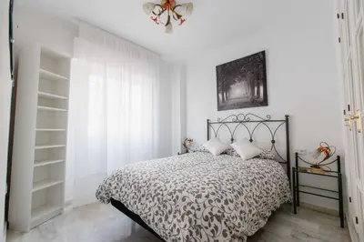 a bedroom with a bed with a black and white comforter at Apartamentos Las Huertas in Cádiz