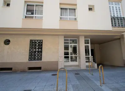 a building with yellow barriers in front of it at Apartamentos Las Huertas in Cádiz