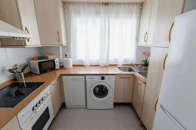 a kitchen with a washing machine and a microwave at Apartamentos Las Huertas in Cádiz