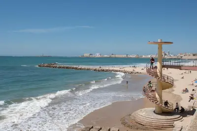a cross on a beach with people on the sand at Apartamentos Las Huertas in Cádiz