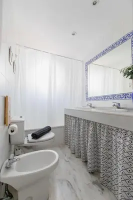 a bathroom with a toilet and a sink and a mirror at Apartamentos Las Huertas in Cádiz