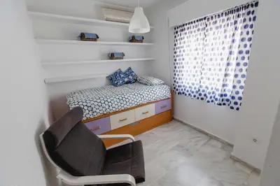 a small bedroom with a bed and a chair at Apartamentos Las Huertas in Cádiz
