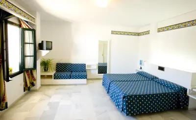a bedroom with two blue beds and a window at Los Helechos in Sanlúcar de Barrameda