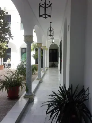 a hallway of a building with pillars and plants at Los Helechos in Sanlúcar de Barrameda