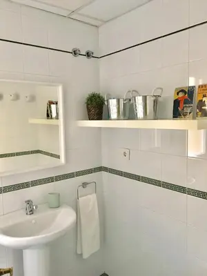 a white bathroom with a sink and a mirror at Apartamento Costa Ballena in Rota
