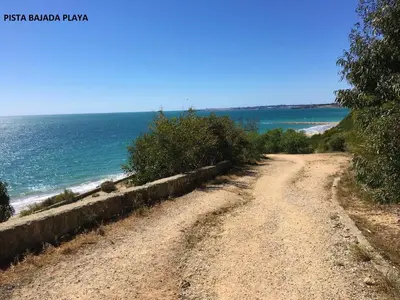 a dirt road near the ocean on a sunny day at Apartamentos Bahía Blanca in El Puerto de Santa María