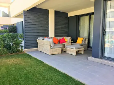 a patio with two wicker chairs and a table at Apartamentos Bahía Blanca in El Puerto de Santa María