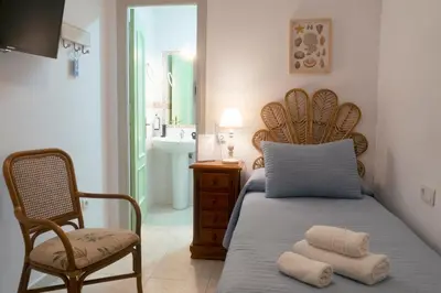 a bedroom with a bed and a chair and a sink at Rompeolas Playa in Chipiona