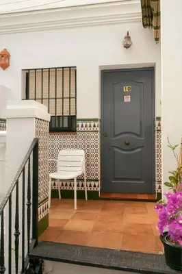 a blue door on a porch with a white chair at Rompeolas Playa in Chipiona