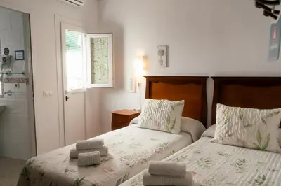 a bedroom with two beds and a bathroom with a shower at Rompeolas Playa in Chipiona