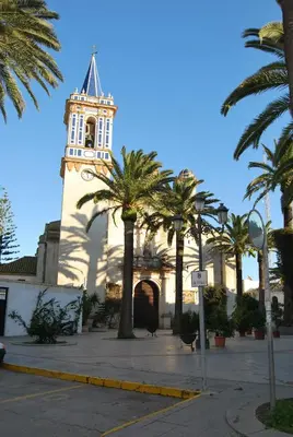 a building with a clock tower with palm trees in front at Hostal Avenida by Bossh! Hotels in Chipiona
