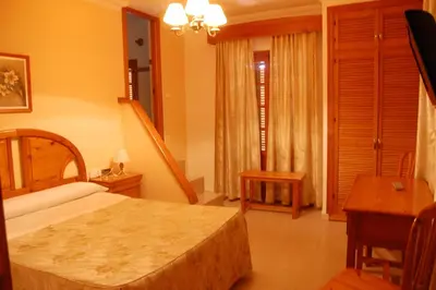 a bedroom with a bed and a table and a desk at Hotel Antonio Conil in Conil de la Frontera