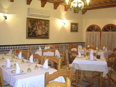 a dining room with white tables and chairs and a painting at Hotel Antonio Conil in Conil de la Frontera