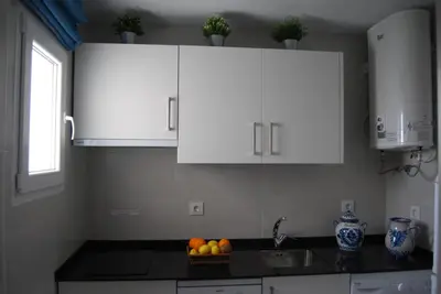 a kitchen with white cabinets and a bowl of fruit on the counter at La casa De Los Faros in El Puerto de Santa María