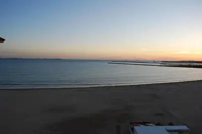 a beach with a pier and the ocean at sunset at La casa De Los Faros in El Puerto de Santa María