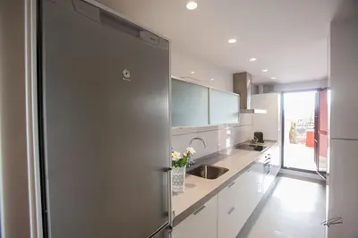 a kitchen with white cabinets and a stainless steel refrigerator at Casa Manzanilla in Sanlúcar de Barrameda