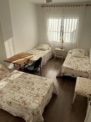 a room with three beds and a table and a desk at Chalet a 100m de la playa en El Puerto in El Puerto de Santa María