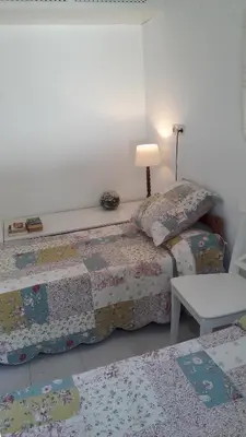 a bedroom with two beds and a table and a lamp at Chalet a 100m de la playa en El Puerto in El Puerto de Santa María