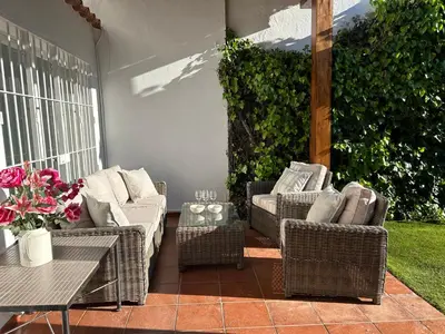 a patio with wicker chairs and a table with a table at Chalet a 100m de la playa en El Puerto in El Puerto de Santa María