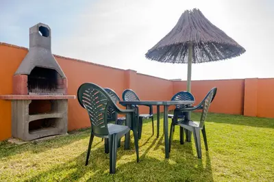 a table and chairs and an umbrella on a yard at Hacienda Puerto Conil in Conil de la Frontera