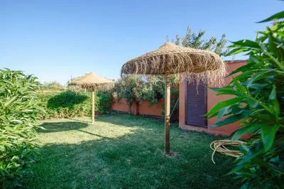two straw umbrellas in a yard next to a building at Hacienda Puerto Conil in Conil de la Frontera