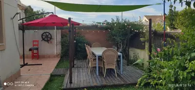 a patio with a table and chairs under a red umbrella at La Pavona 11 - 1ª línea de Playa Chipiona in Chipiona