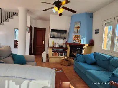 a living room with a blue couch and a ceiling fan at La Pavona 11 - 1ª línea de Playa Chipiona in Chipiona