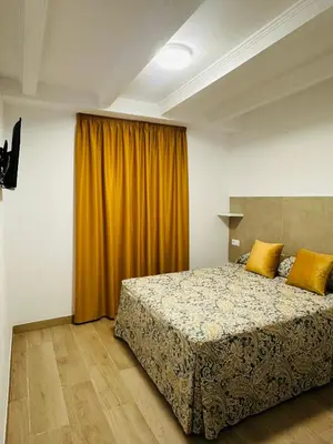 a bedroom with a bed and a yellow curtain at Hotel Quitagolpe in Jerez de la Frontera