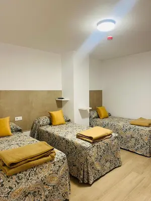 a room with three beds with yellow pillows on them at Hotel Quitagolpe in Jerez de la Frontera