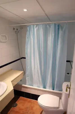 a bathroom with a blue shower curtain and a toilet at Apto en Residencial El Bosque in Chiclana de la Frontera