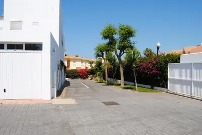 an empty street with a white fence and trees at Apto en Residencial El Bosque in Chiclana de la Frontera