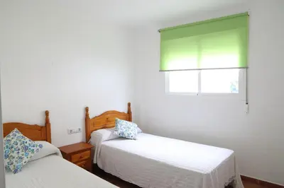 a bedroom with two beds and a window at Apto en Residencial El Bosque in Chiclana de la Frontera