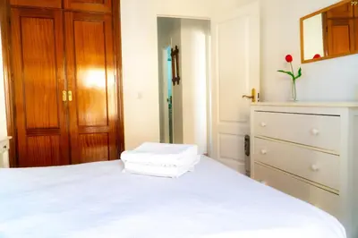 a bedroom with a white bed and a dresser at Light House Sherry in Jerez de la Frontera