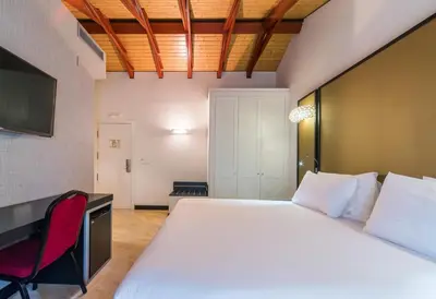 a bedroom with a large white bed and a red chair at Hotel Palacio Marqués de Arizón in Sanlúcar de Barrameda